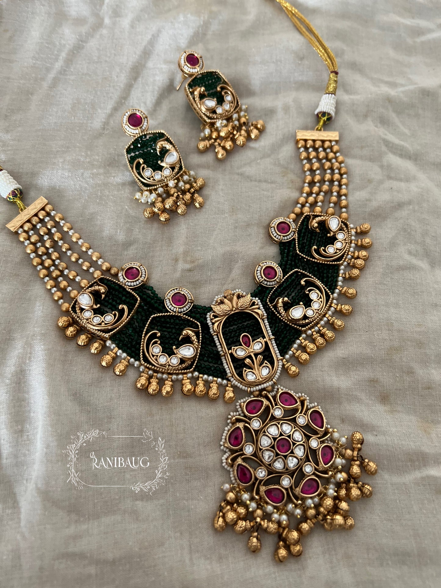 Shyama Gold Finish Peacock Motif Deep Green And Ruby Adorned Polki Heritage Jewellery Set By Ranibaug